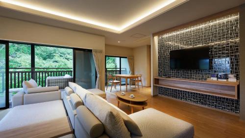 a living room with a couch and a tv on a wall at 鹿覗きの湯つるや in Nakanojo