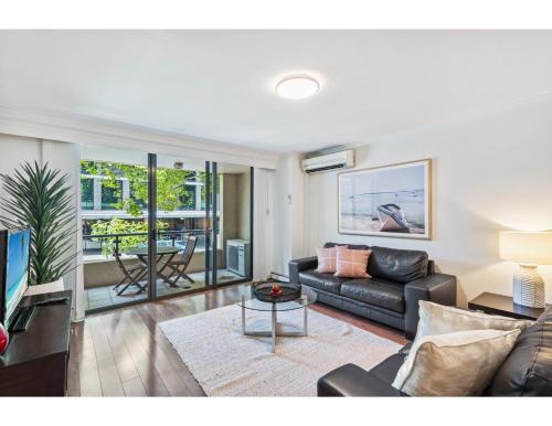 a living room with a couch and a table at Poolside 2-Bed Haven, Walk to City Centre in Sydney