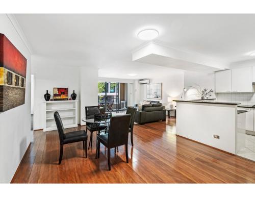 a kitchen and a living room with a table and chairs at Poolside 2-Bed Haven, Walk to City Centre in Sydney