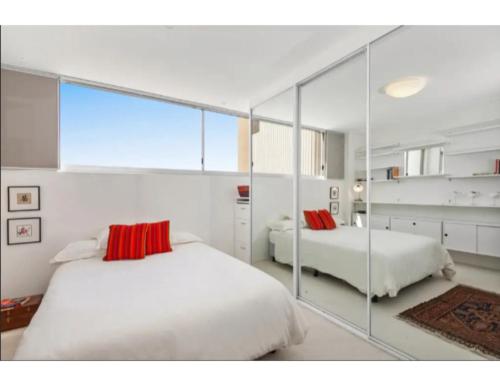 a bedroom with two beds and a large mirror at Beachside Paradise - Ocean Views, Central Position in Sydney