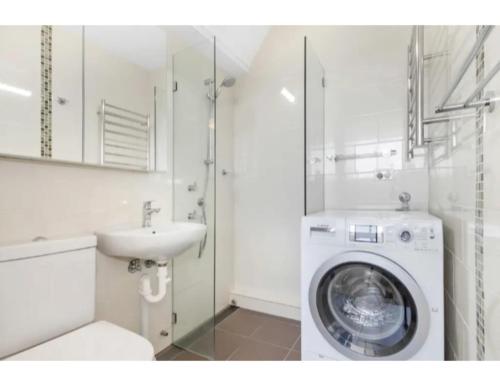 a white bathroom with a washing machine and a sink at Beachside Paradise - Ocean Views, Central Position in Sydney