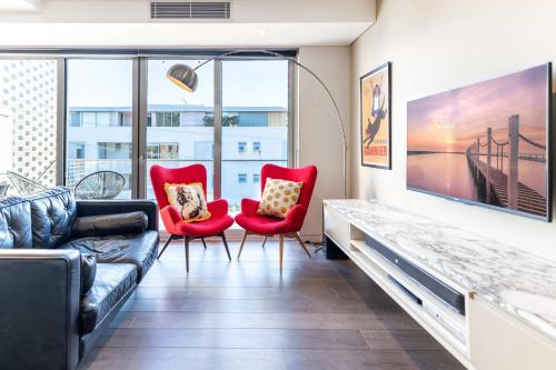 a living room with a couch and two red chairs at Comfy 1-Bed Apartment in Perfect Location in Sydney
