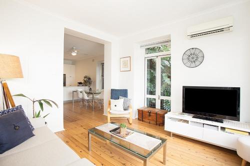 a white living room with a large tv and a couch at Harbourside - Unforgettable Destination in Sydney