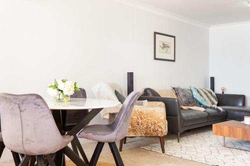 a living room with a couch and a table and chairs at Beachfront Manly Apartment With Balcony & Parking in Sydney
