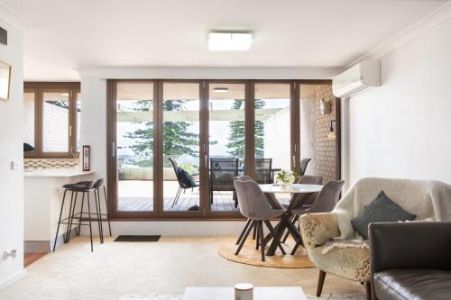 a living room with a table and chairs at Beachfront Manly Apartment With Balcony & Parking in Sydney