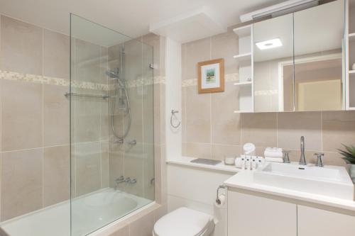 a bathroom with a shower and a toilet and a sink at Beachfront Manly Apartment With Balcony & Parking in Sydney