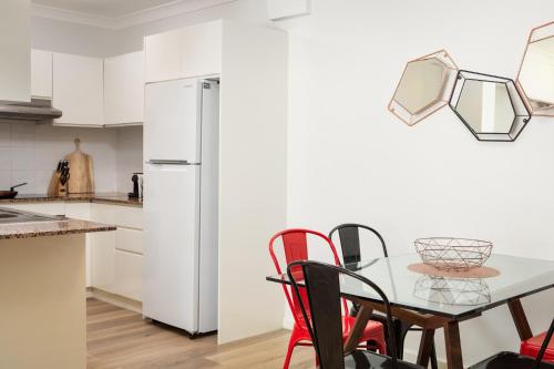 a kitchen with a table with chairs and a refrigerator at Suburban Two-bed Apartment with Parking and Patio in Sydney