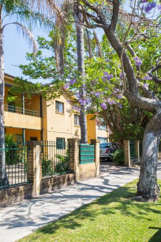 a tree with purple flowers in front of a building at Suburban Two-bed Apartment with Parking and Patio in Sydney