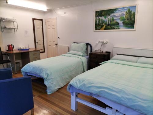 a bedroom with two beds and a desk with a lamp at 别墅中的一间客房 in Auckland
