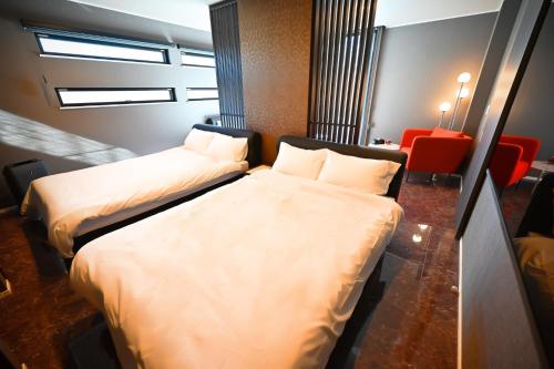 a hotel room with two beds and a red chair at 8Room - Vacation STAY 70870v in Yachimata