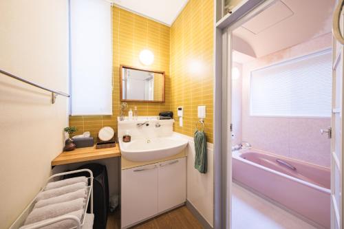 ein Badezimmer mit einem Waschbecken und einer rosa Badewanne in der Unterkunft Jomo Stay Takasaki 2 -the Garden- in Takasaki
