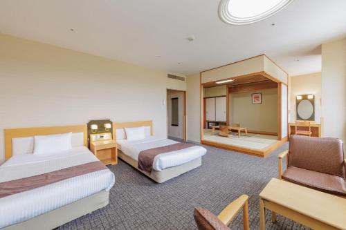 a hotel room with two beds and a chair at KAMENOI HOTEL Ichinoseki in Ichinoseki
