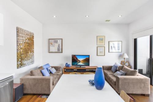 a living room with two couches and a tv at 2-Bed Apartment with Parking & Balcony Near Trains in Yarraville