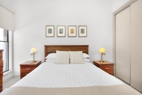 a bedroom with a large white bed with two lamps at 2-Bed Apartment with Parking & Balcony Near Trains in Yarraville