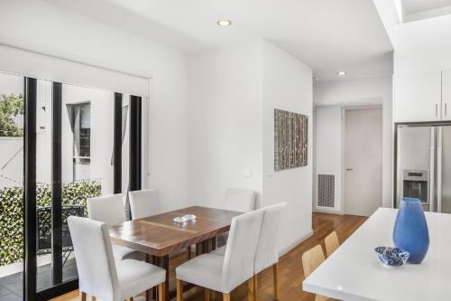 a dining room with a wooden table and white chairs at 2-Bed Apartment with Parking & Balcony Near Trains in Yarraville