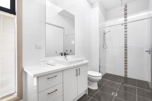 a white bathroom with a sink and a toilet at 2-Bed Apartment with Parking & Balcony Near Trains in Yarraville
