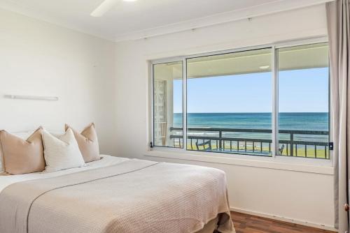 Absolute Beachfront Apartments 3T في لينوكس هيد: غرفة نوم مع سرير وإطلالة على المحيط