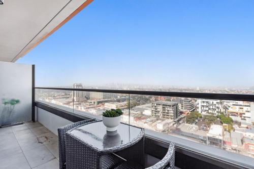 a balcony with a table and chairs and a view of a city at Chic 1-Bed with City Views Parking Gym & Pool in Melbourne