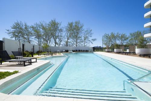 a large swimming pool with benches and a building at Modern 1-Bed Apartment With Parking, Pool and Gym in Phillip