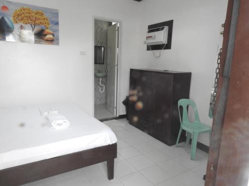 a bathroom with a bed and a green chair at Pacifico Seaside Lodge in Moalboal
