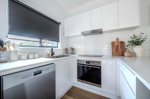a white kitchen with a stove and a dishwasher at Tamworth Loft - Cosy & Convenient, Ideal for Work in Dubbo