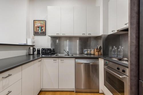 a kitchen with white cabinets and stainless steel appliances at Beautiful 2-Storey Unit with Balcony near Smith St in Melbourne