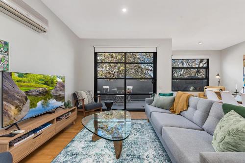 a living room with a couch and a large tv at Beautiful 2-Storey Unit with Balcony near Smith St in Melbourne