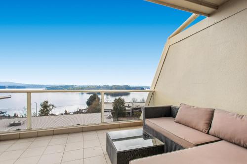 eine Couch auf einem Balkon mit Blick auf das Wasser in der Unterkunft 2-Bed Unit with Balcony BBQ & Stunning Lake Views in Belconnen