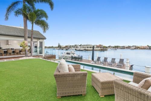 a yard with wicker chairs and a swimming pool at Amazing Canal House with Private Jetty, Gym & Pool in Mooloolaba