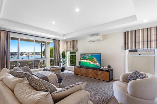 a living room with a couch and a tv at Amazing Canal House with Private Jetty, Gym & Pool in Mooloolaba