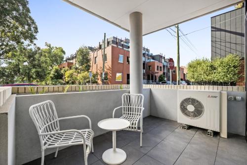 a balcony with two chairs and a table and a fan at Bright Terrace Unit Next to Chapel St Dining in Melbourne