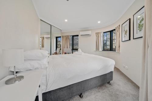 a white bedroom with two beds and a mirror at Central 2-bed Apartment with Pool, Gym and Spa in Canberra