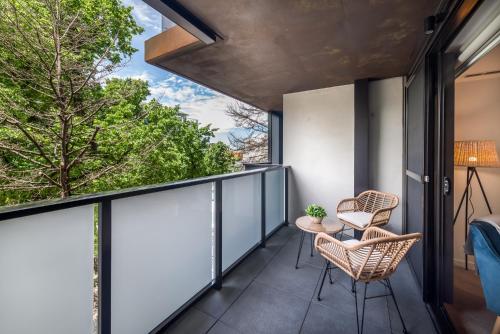a balcony with two chairs and a table at Chic 3-Bed in Central with Pool, Sauna and Gym in Canberra