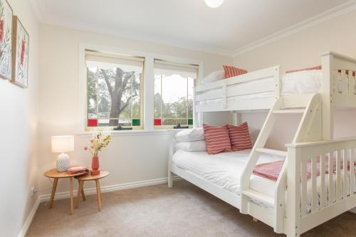 a white bedroom with a bunk bed and a table at Stunning Katoomba Home with Lush Garden&Playground in Katoomba