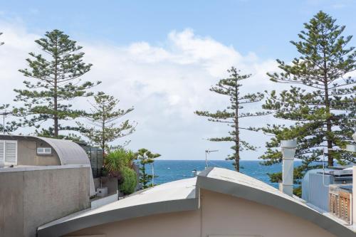 a view of the ocean from a balcony with trees at MadeComfy Trendy Apartment on Dee Why Beach in Deewhy