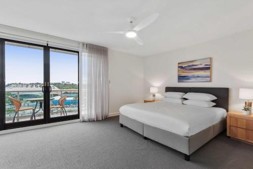 a white bedroom with a bed and a balcony at Spacious 3-Bed Apartment by the MCG in Melbourne