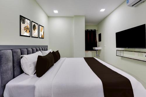 a bedroom with a large white bed and a flat screen tv at Hotel O Krishna Riverview Vijayawada Formerly Sikara in Krishna Canal