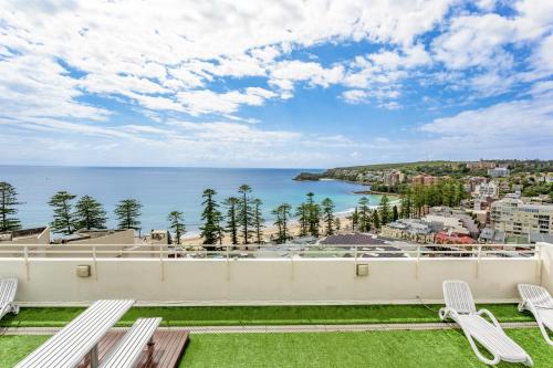 a balcony with white chairs and a view of the ocean at Modern Manly Apartment with Stunning Views, Pool in Sydney