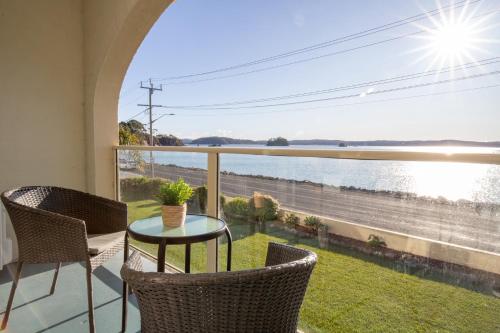 a balcony with a table and chairs and a view of the water at Batemans Bay Studio Escape with Lush Vista in Batehaven