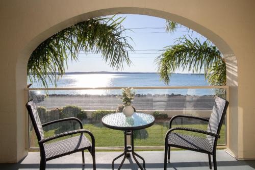a table and two chairs in front of a large window at Seafront Getaway Studio, Great Location with Pool in Batehaven