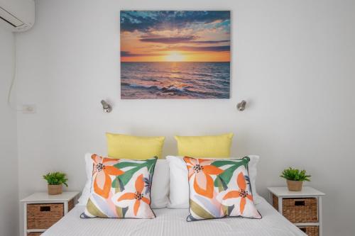 a bedroom with a bed with a painting on the wall at Seafront Getaway Studio, Great Location with Pool in Batehaven