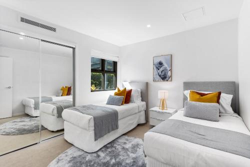 a white room with two beds and a mirror at Spacious and Superb 3-bed Apartment in Brisbane