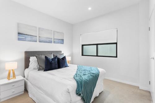 a white bedroom with a large bed with blue pillows at Spacious and Superb 3-bed Apartment in Brisbane