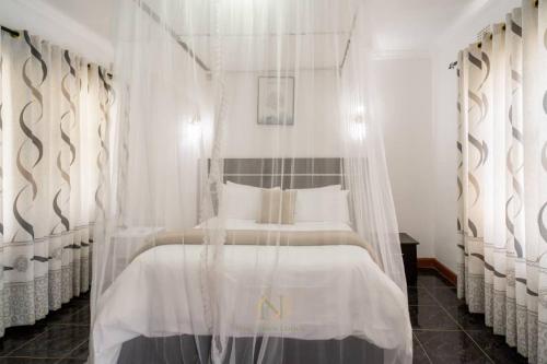 a bedroom with a canopy bed with white curtains at New Dawn Lodge in Lilongwe