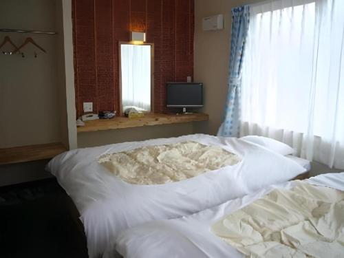 a bedroom with a white bed and a television at Business Hotel Tsuwano in Tsuwano
