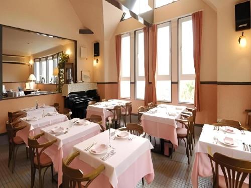 ein Restaurant mit weißen Tischen und Stühlen und Fenstern in der Unterkunft Country Inn The White Marine in Fuchisaki