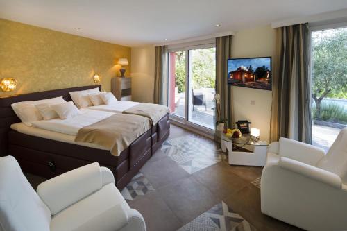 a bedroom with a bed and two chairs and a tv at Boutique Hotel Albergo Brione in Locarno