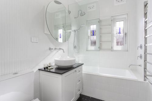 a white bathroom with a sink and a tub and a mirror at Coastal Living Just Metres From Coogee Beach in Sydney