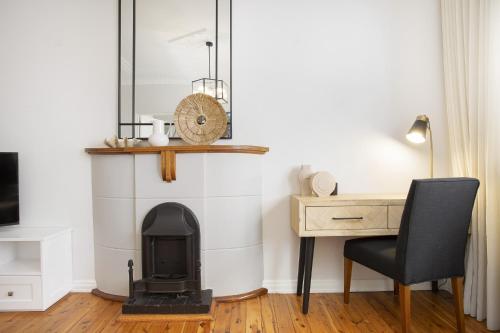a room with a fireplace and a desk and a chair at Coastal Living Just Metres From Coogee Beach in Sydney