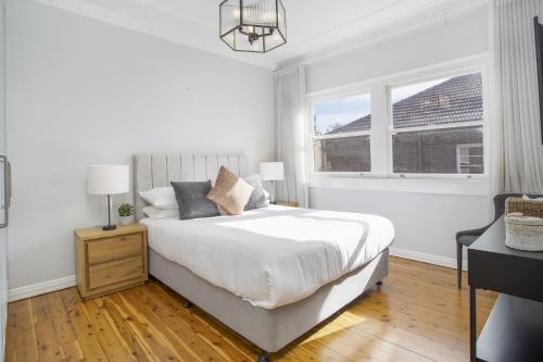 a white bedroom with a bed and a window at Coastal Living Just Metres From Coogee Beach in Sydney